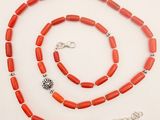 a close up of a necklace and bracelet on a white surface
