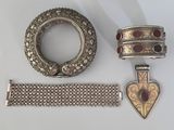 bracelet en argent, bague et bracelet ornés de pierres rouges sur un fond blanc
