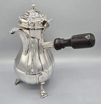 an antique silver coffee pot with a wooden handle on a grey background