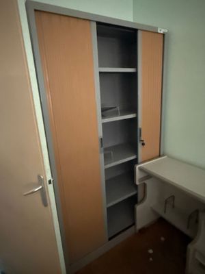 un placard situé dans un coin d'une pièce où se trouvent un bureau et une chaise