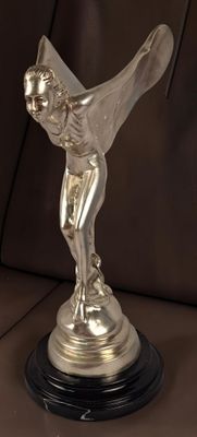 une statue en argent représentant une femme tenant un oiseau, posée sur une table