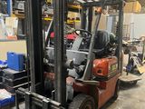 un chariot élévateur dans un entrepôt où se trouvent de nombreux cartons au sol