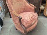an old chair with a pink velvet upholstered and a wooden arm rest