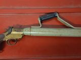 an old gun on display in a glass case on a red surface