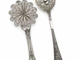 two silver spoons and a spoon with a flower on them