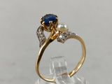 a close up of a gold ring with a sapphire and a pearl
