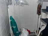 un porte-vêtements blanc sur lequel sont suspendus des vêtements, dans une salle de bains