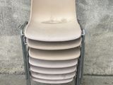 une pile de chaises assises sur un trottoir à côté d'un mur