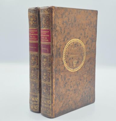 un vieux livre posé sur une table blanche à côté d'un livre rouge