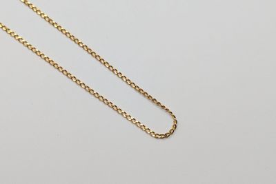 un collier à chaîne en or orné d'un seul diamant sur fond blanc
