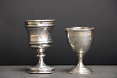 deux gobelets en argent posés l'un à côté de l'autre sur une table
