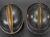 pair of black helmets with gold trims on a black surface