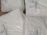 four bags of white pillows sitting on top of a wooden table