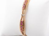 a close up of a gold bracelet with pink stones on it