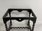 an old black table with a glass top on a white floor