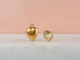 une paire de boucles d'oreilles en forme de cœur en or posées sur une surface en marbre