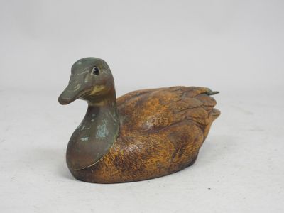 bronze colored duck figurine sitting on a white surface