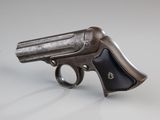 un vieux pistolet en forme de pistolet posé sur une surface blanche