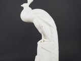 a white sculpture of a peacock sitting on top of a rock
