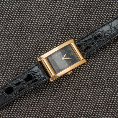 un gros plan d'une montre noire et dorée posée sur une surface noire
