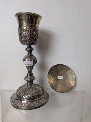 a silver cup sitting on a table next to a silver plate