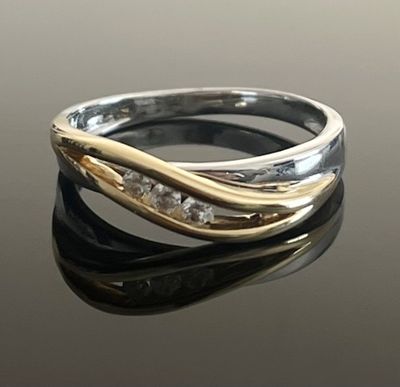 un gros plan d'une bague en or et en argent posée sur une surface noire