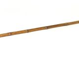 une vieille crosse de hockey avec un manche en bois posée sur une surface blanche