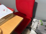 a red chair next to a desk with a book on it