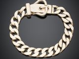 un bracelet en or muni d'un fermoir, sur fond noir