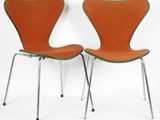 pair of orange chairs with chrome legs against a white background