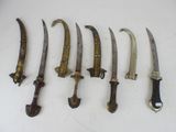 several knives are lined up on a white surface with a knife in the middle