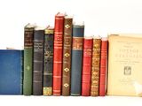 Plusieurs livres anciens sont alignés sur une étagère devant un fond blanc