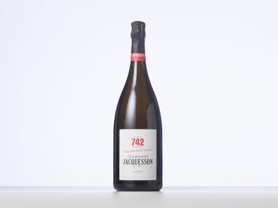 une bouteille de vin posée sur une table à côté d'un mur blanc