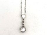 un gros plan d'un pendentif en diamant suspendu à une chaîne, posé sur une surface blanche
