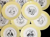 yellow and white plates with black drawings on them on a black surface