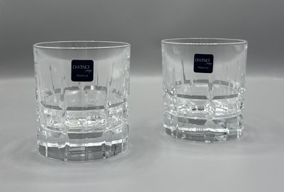 une paire de verres à eau en verre transparent, ornés d'étiquettes noires, posés sur une surface blanche