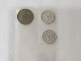 three coins in a plastic bag on a white surface