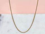 un collier à chaîne en or sur fond rose