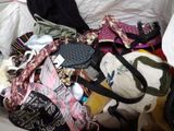 a pile of clothes and bags sitting on a bed