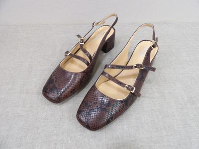 une paire d'escarpins en peau de serpent marron posés sur une surface blanche