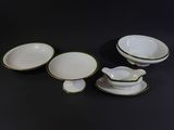 four pieces of white and green china on a black surface