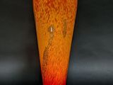 un vase rouge et orange posé sur une surface noire