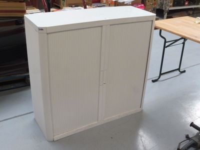 une armoire blanche au milieu d'une pièce, à côté d'une table