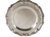 une assiette ancienne en argent, ornée d'un motif décoratif sur fond blanc