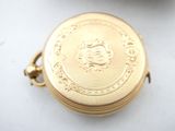 a close up of a gold pocket watch on a white surface