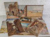 many paintings on a table with a white table cloth