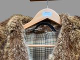 a coat with a fur collar on a hanger