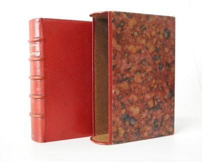 an old book with a red cover sitting open on a white surface