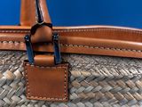 a close up of a woven basket bag with a leather handle