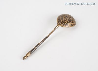 a gold spoon with a handle on a white surface